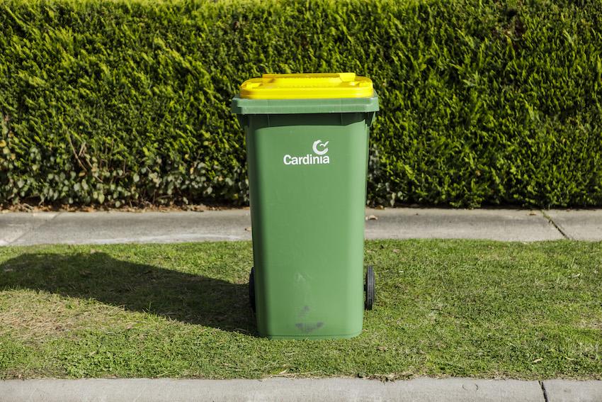 Recycling bin with yellow lid on kerb